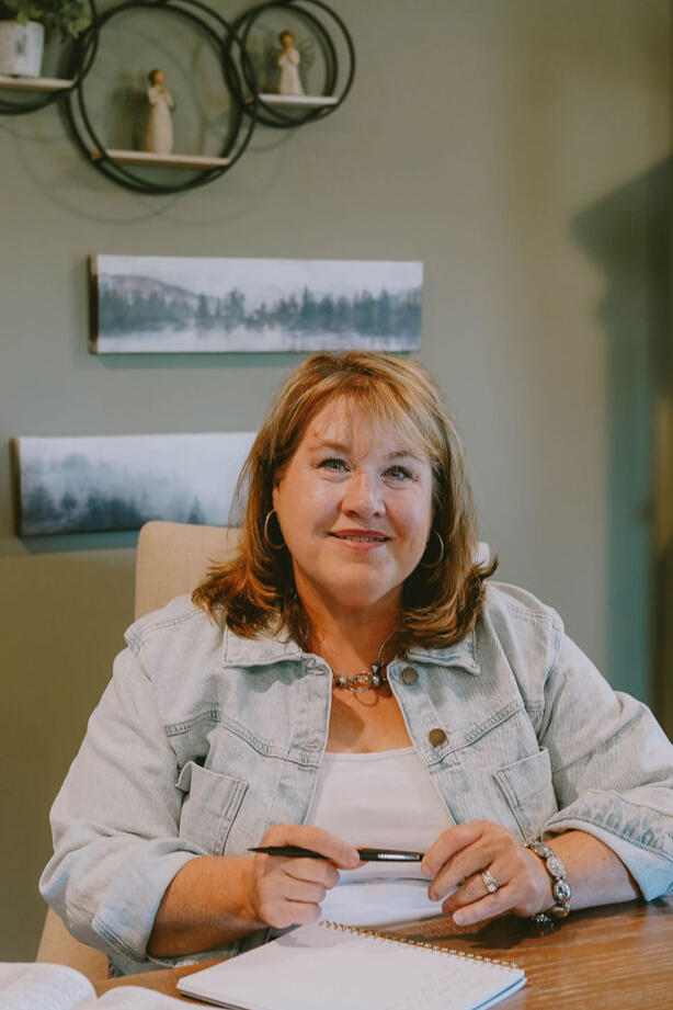 Shara Neubert seated at a table with a notebook and open Bible.